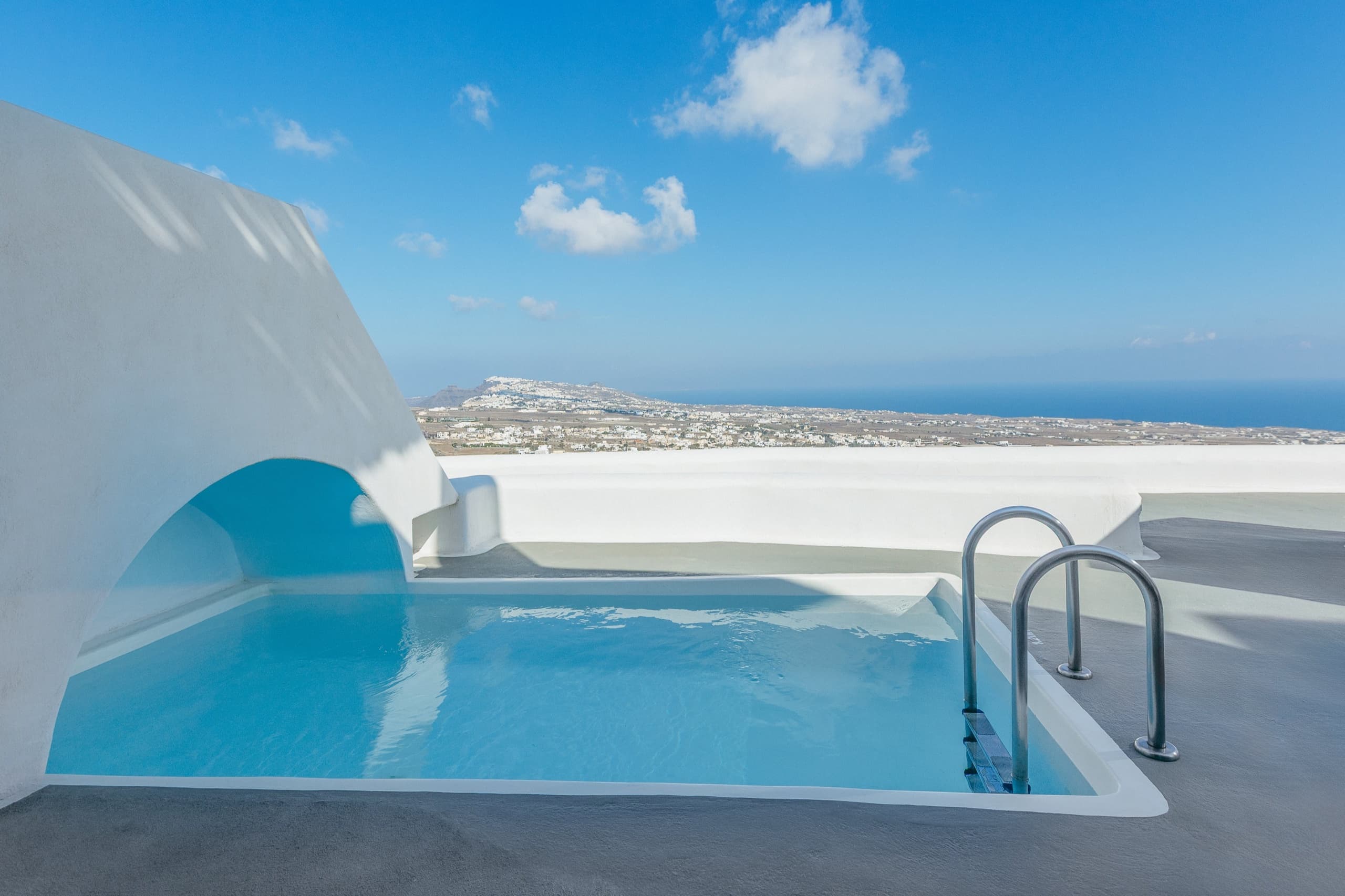 A private pool under a whitewashed arch on a terrace at Carpe Diem Santorini, looking out over the island to the sea