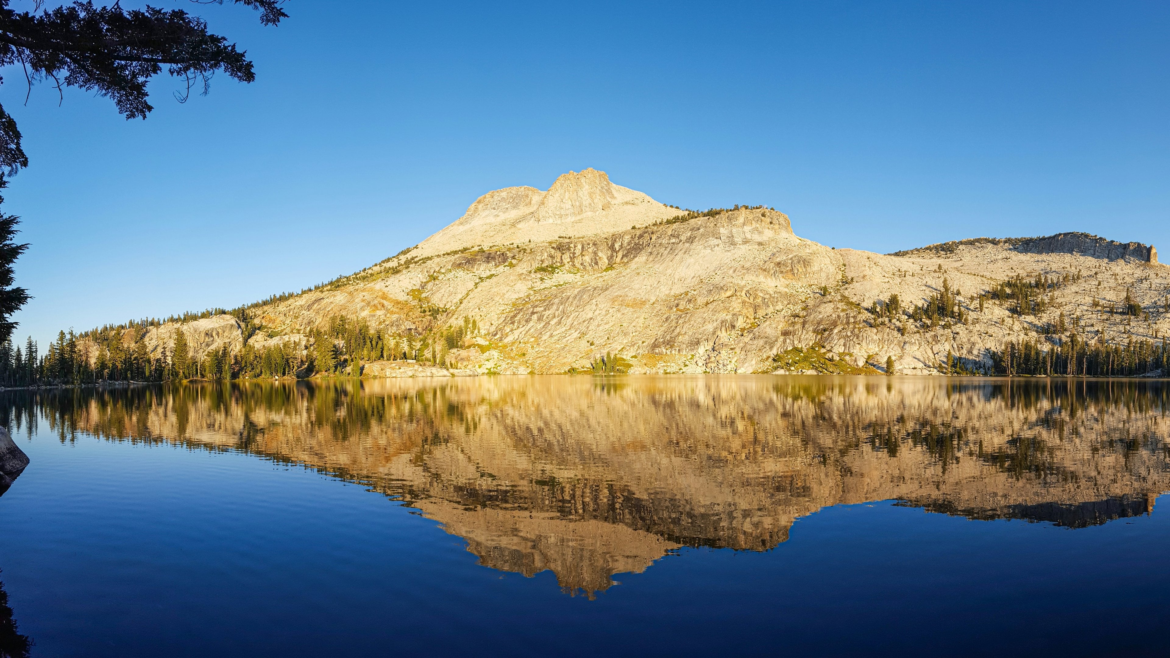 A granite dome reflected in a deep-blue mountain lake